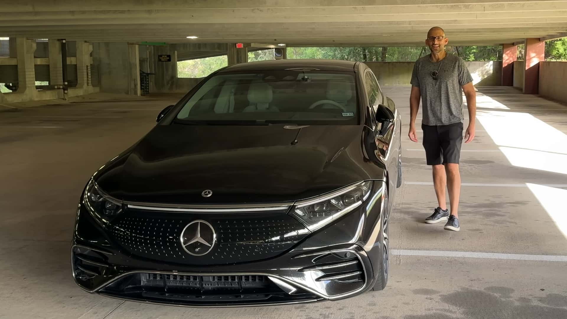 Mand står ved siden af en sort Mercedes elbil i en parkeringskælder