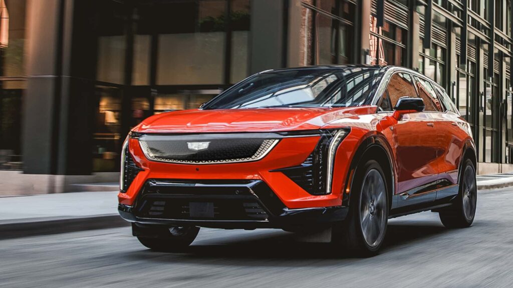 Rød elektrisk SUV kører på en byvej foran moderne bygninger