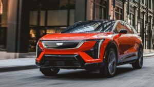 Rød elektrisk SUV kører på en byvej foran moderne bygninger