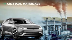 Elektrisk bil foran industriområde under overskyet himmel