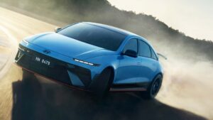Blå elektrisk sedan fra Hyundai kører hurtigt i en sving på en støvet vej