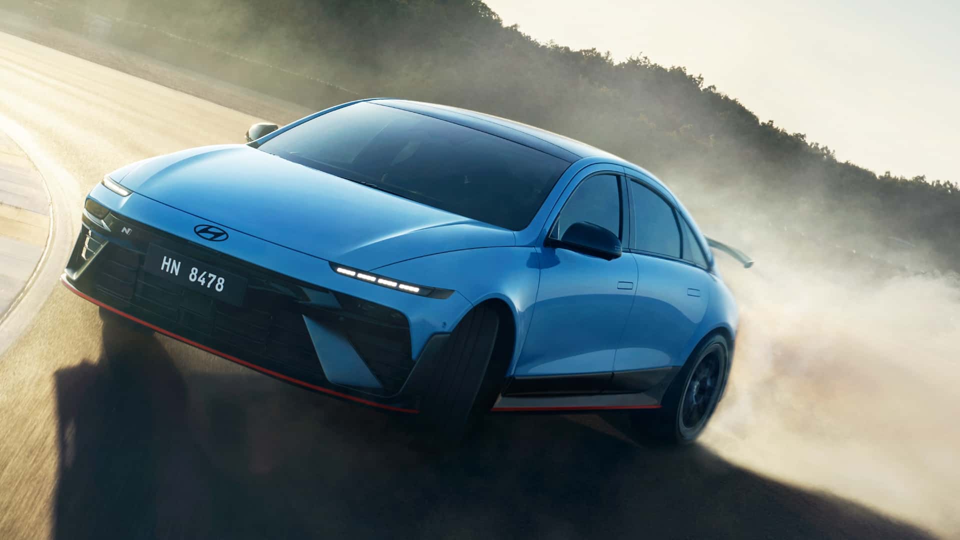 Blå elektrisk sedan fra Hyundai kører hurtigt i en sving på en støvet vej