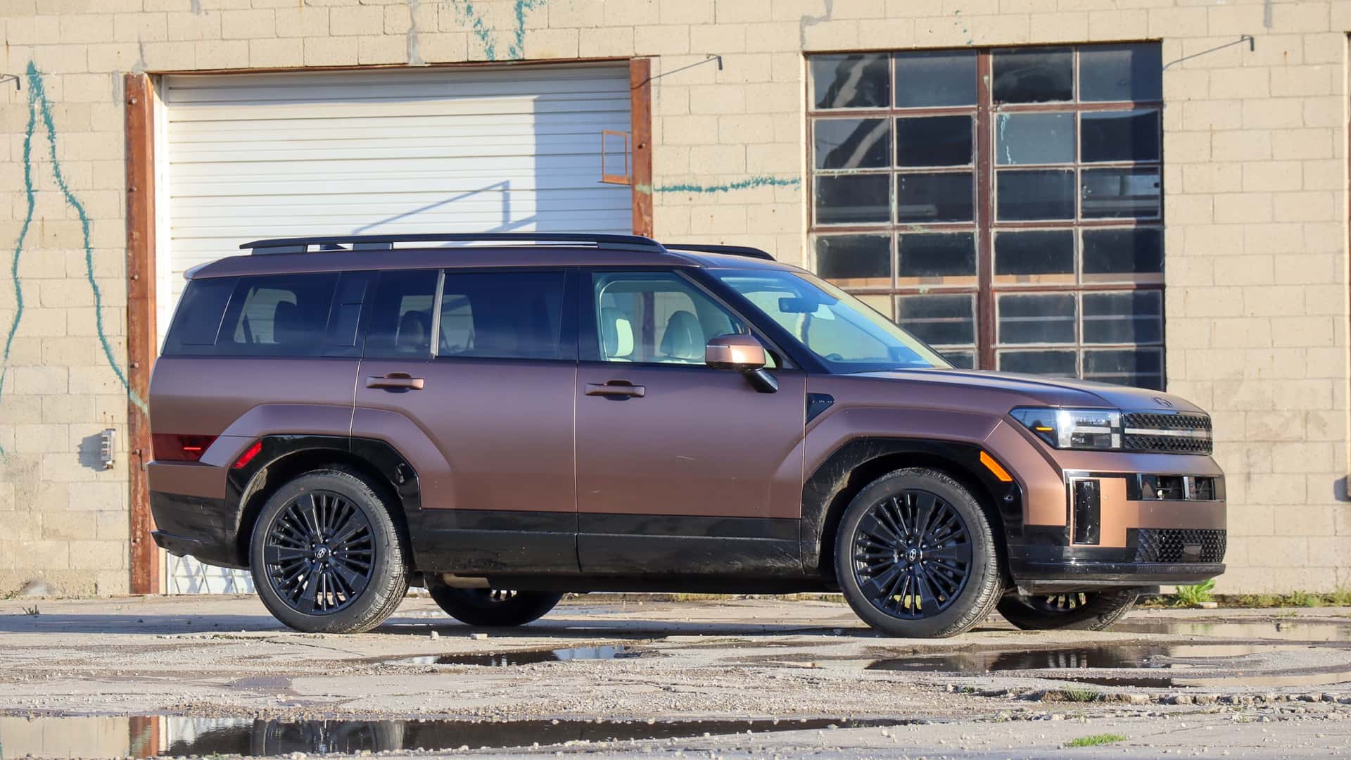 Elektrisk SUV i bronze står parkeret foran en gammel industribygning