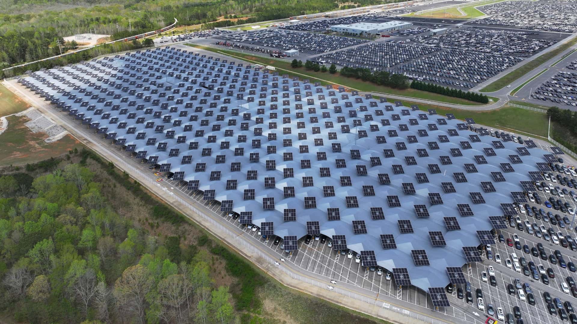 Solcellepaneler på parkeringsplads ved Tesla-anlæg omgivet af skov