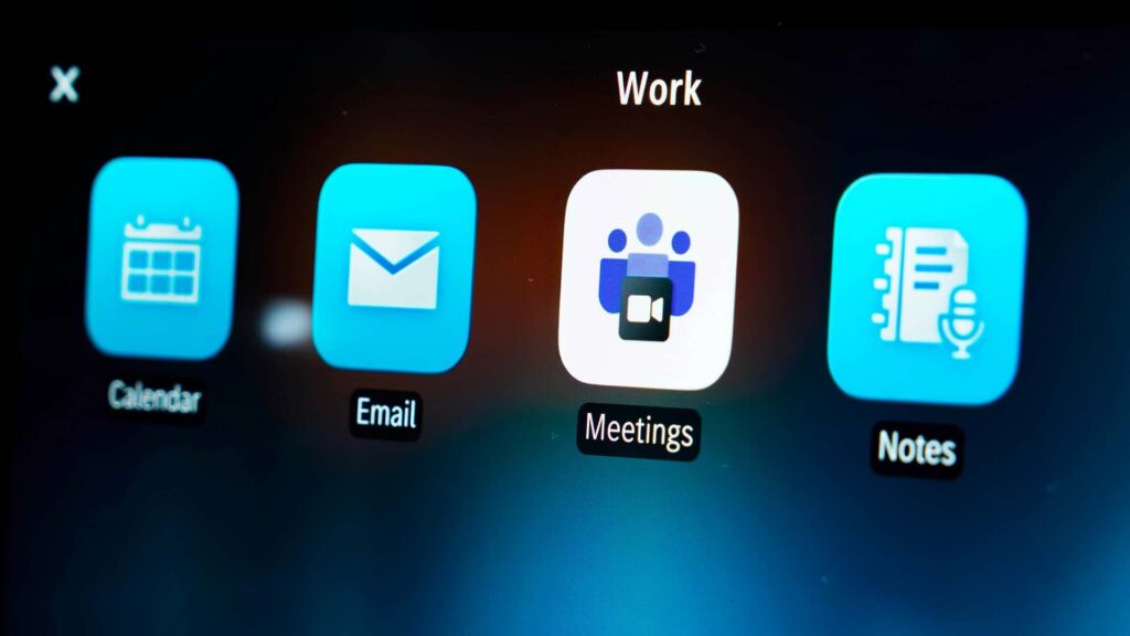 Nærbillede af en skærm med apps til kalender, e-mail, møder og noter, set i en Tesla bil.