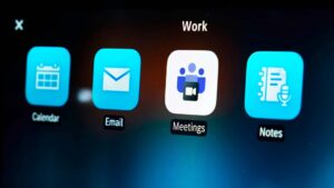 Nærbillede af en skærm med apps til kalender, e-mail, møder og noter, set i en Tesla bil.
