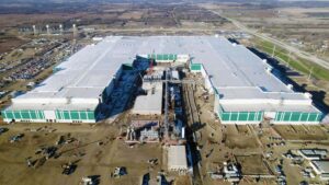 Luftfoto af Teslas Gigafactory under konstruktion, der viser en stor industrihal omgivet af åbent landskab