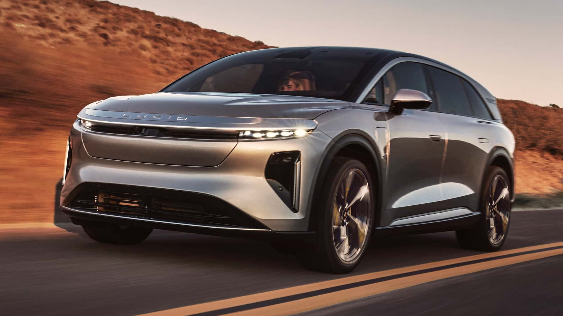 Elektrisk bil kører på landevej med bakker i baggrunden