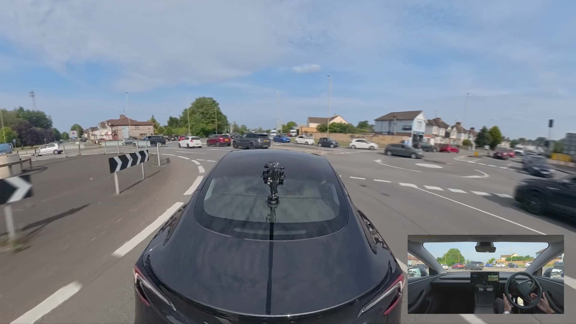 Tesla kører gennem en rundkørsel med et kamera monteret på taget, indvendig visning i en indsat boks.