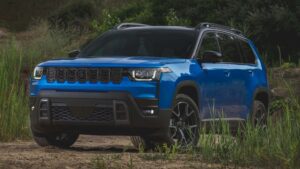 Blå SUV parkeret i naturskønne omgivelser med træ og planter i baggrunden