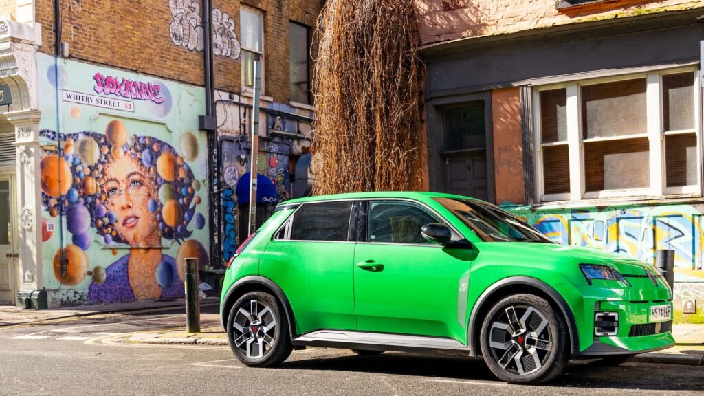 Grøn elbil parkeret på en farverig gade med gadekunst i baggrunden