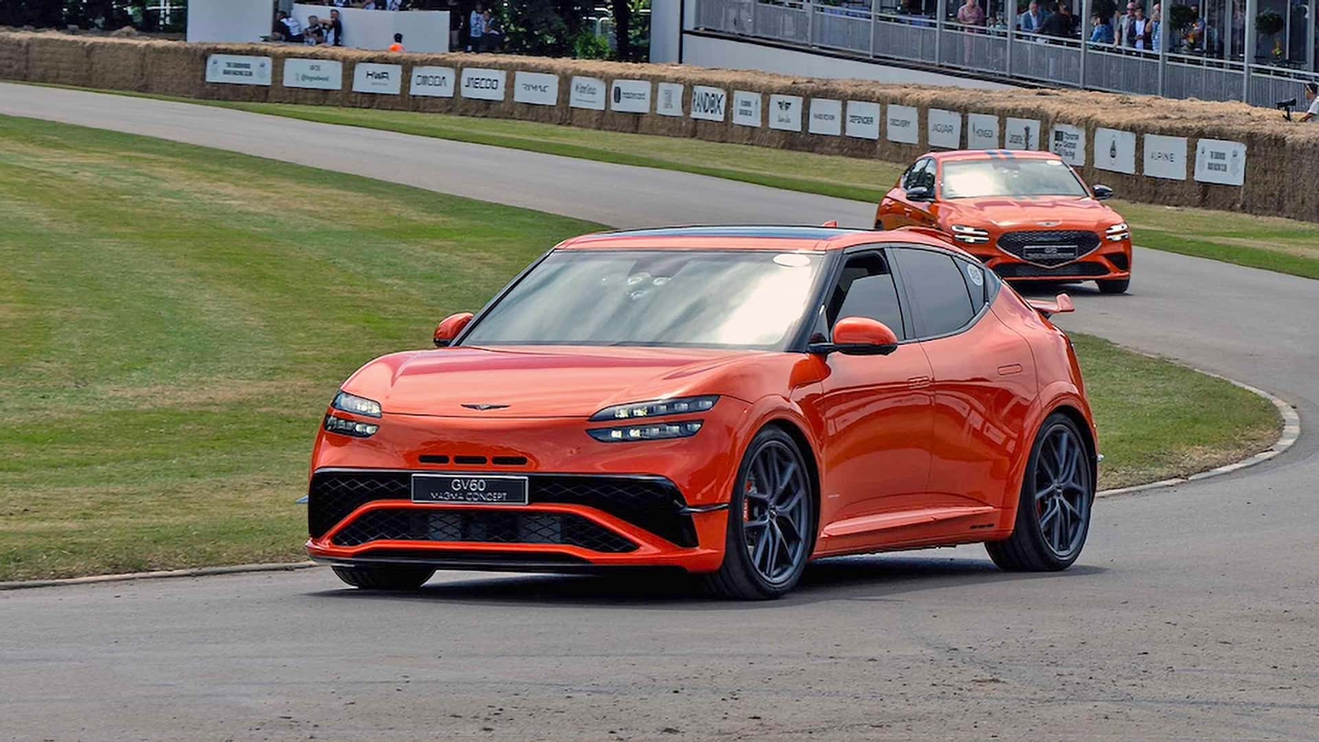 To orange elektriske biler på en racerbilbane under et bilshow