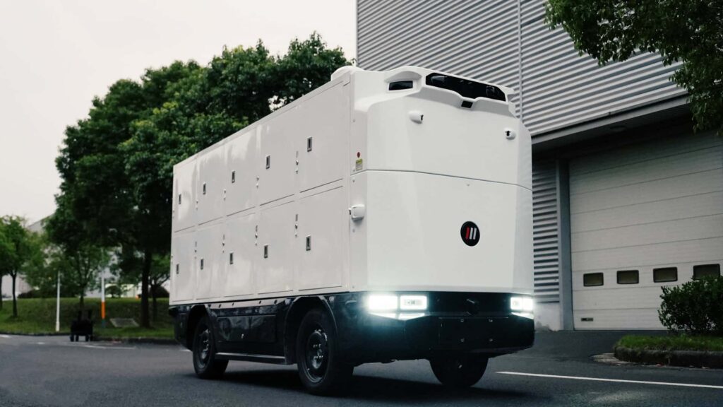 Futuristisk elektrisk lastbil kører på vej ved siden af moderne bygninger