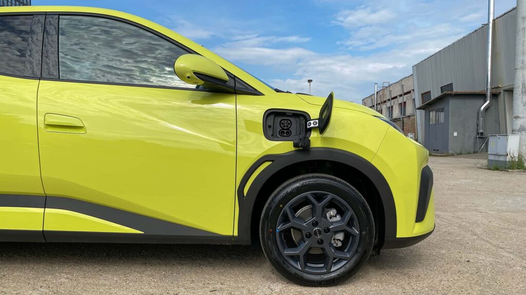 Gul elektrisk bil med åben ladekontakt parkeret udendørs