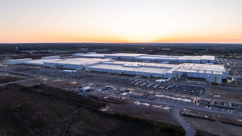 Luftfoto af en stor Tesla-fabrik ved solnedgang