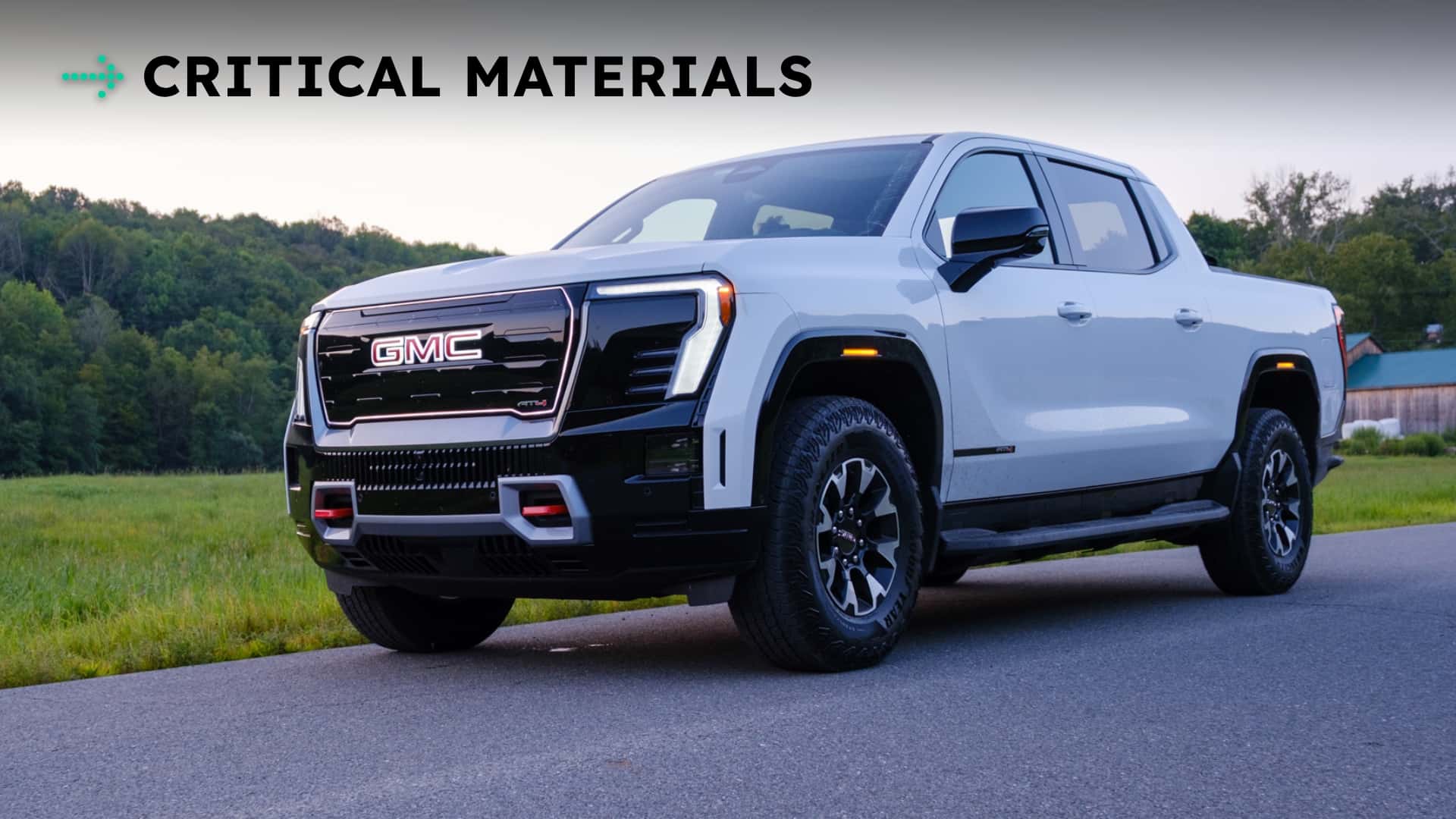 Hvid GMC pickuptruck parkeret på en vej med teksten 'CRITICAL MATERIALS' i baggrunden