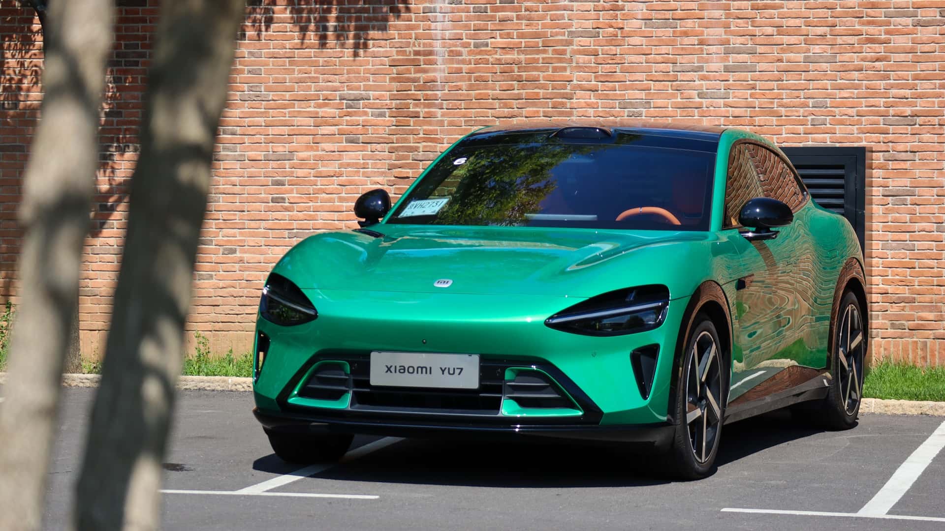Grøn elektrisk bil fra Xiaomi med moderne design parkeret foran en murstensvæg