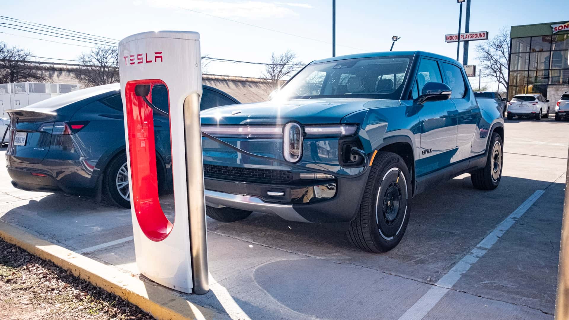 Elektrisk bil ved Tesla ladestation i sollys