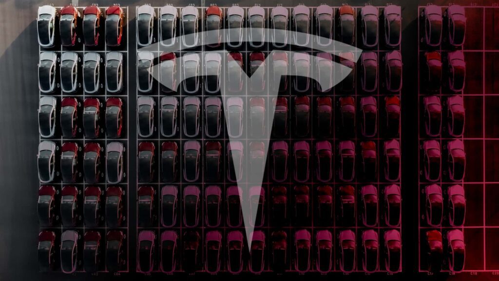 Luftfoto af Tesla biler parkeret i rækker med stort Tesla-logo overlagt