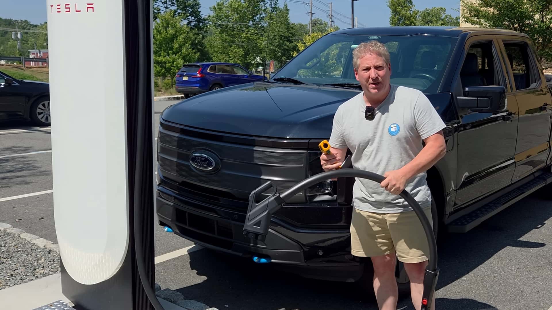 Mand ved siden af en sort elbil holder en Tesla-ladestik