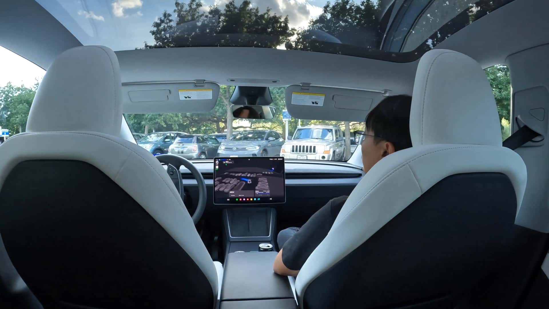 Indvendig udsigt af en Tesla-bil med en central skærm og glaspanoramatag