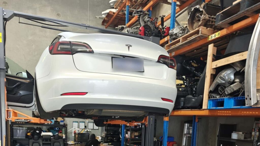 Tesla elbil hævet i værksted med værktøj og reservedele omkring