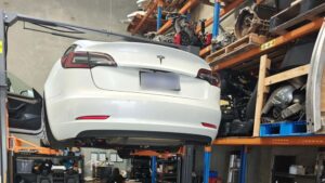 Tesla elbil hævet i værksted med værktøj og reservedele omkring