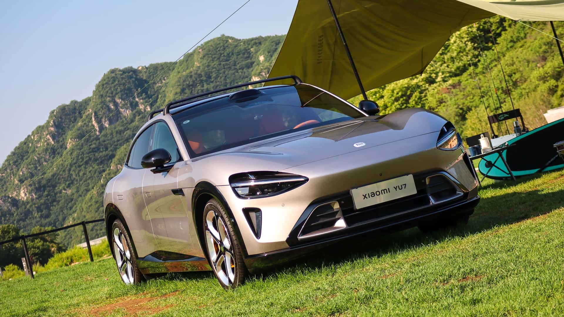 Elektrisk bil på en grøn græsplæne med bjerge i baggrunden