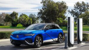 Blå elbil oplader ved Tesla-ladestation omkranset af træer