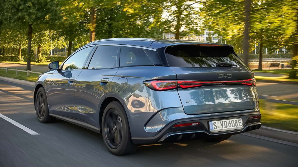 Elektrisk bil kører langs en grøn vej med træer i baggrunden