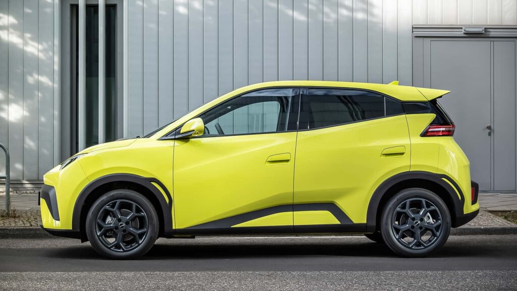 Lys gul elektrisk bil parkeret foran en industriel bygning