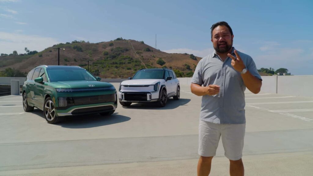 Mand foran to elektriske biler i et solrigt landskab