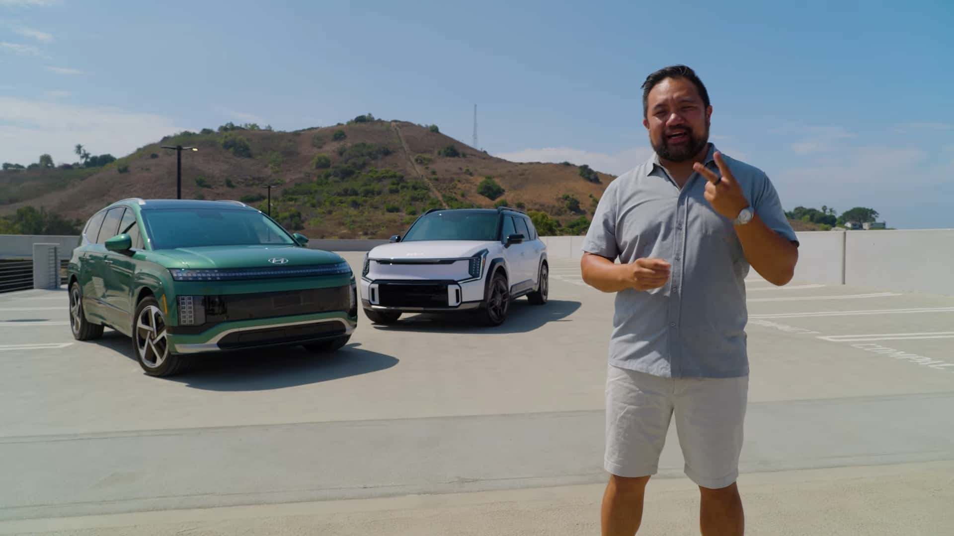 Mand foran to elektriske biler i et solrigt landskab