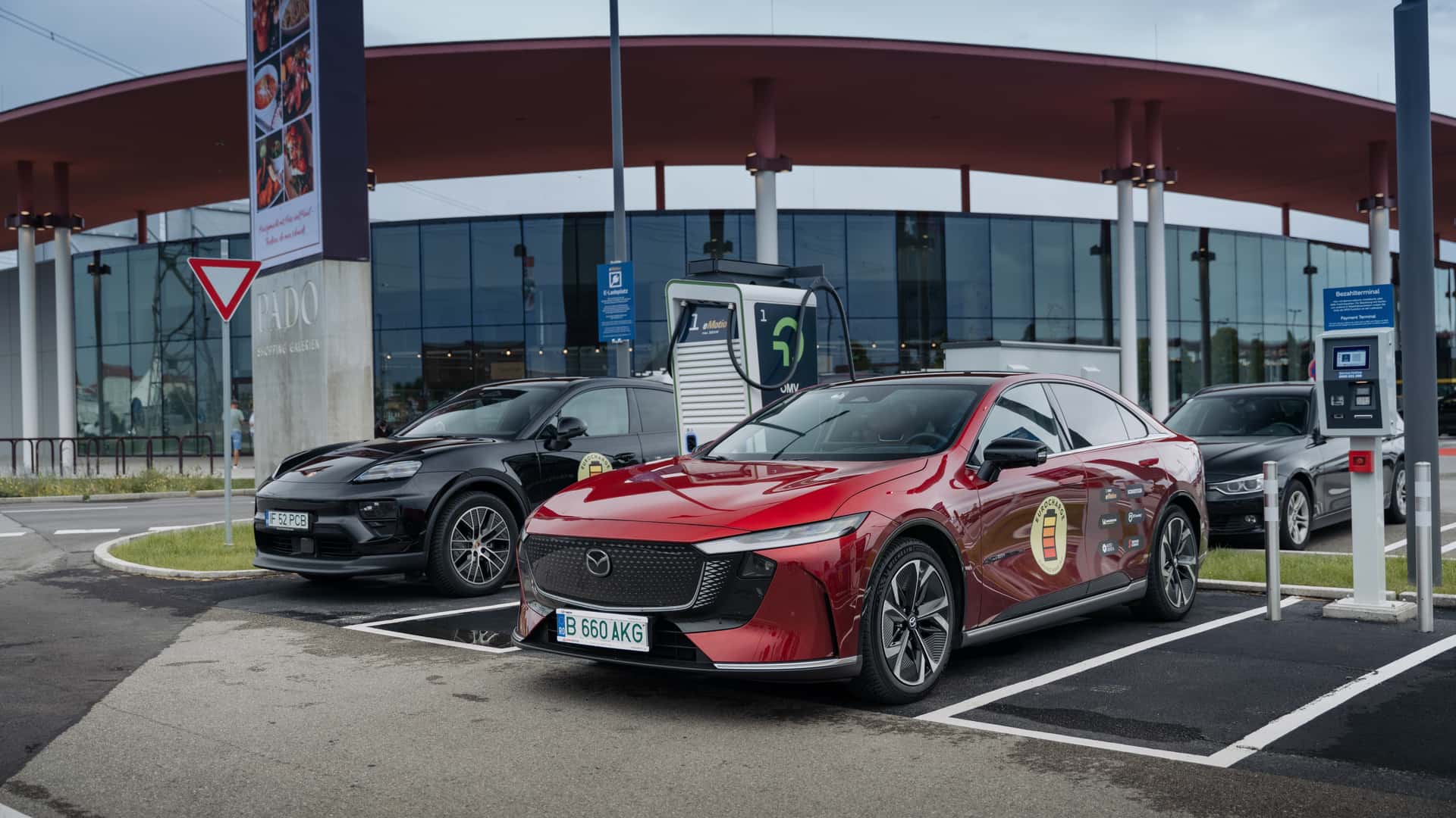 To elektriske biler oplades ved en moderne ladestation foran et stilfuldt bygning.