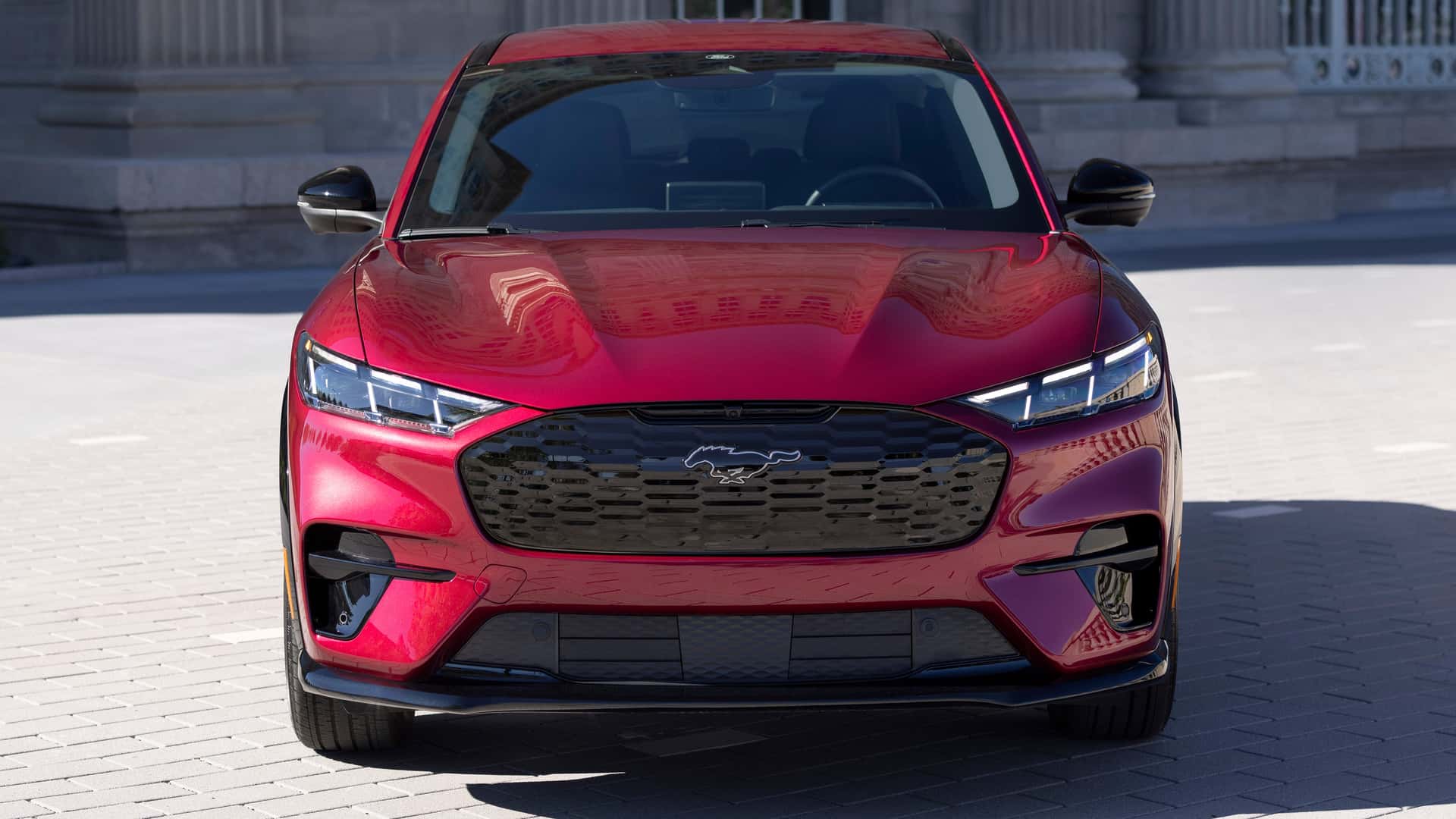 Fronten af en rød elektrisk sportsvogn parkeret foran en bygning.