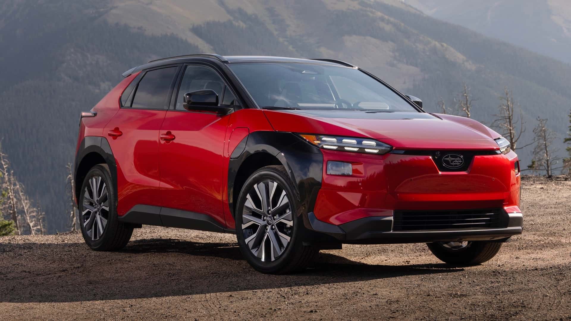 Rød elbil i naturskønne omgivelser med bjerge i baggrunden