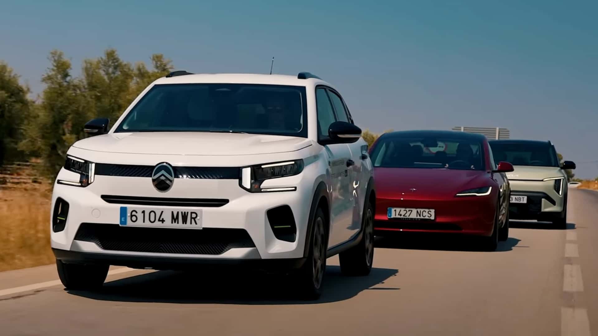 Tre elektriske biler kører på en motorvej i dagslys