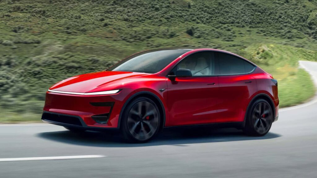 Rød Tesla elbil kører hurtigt på vej i naturskønt landskab