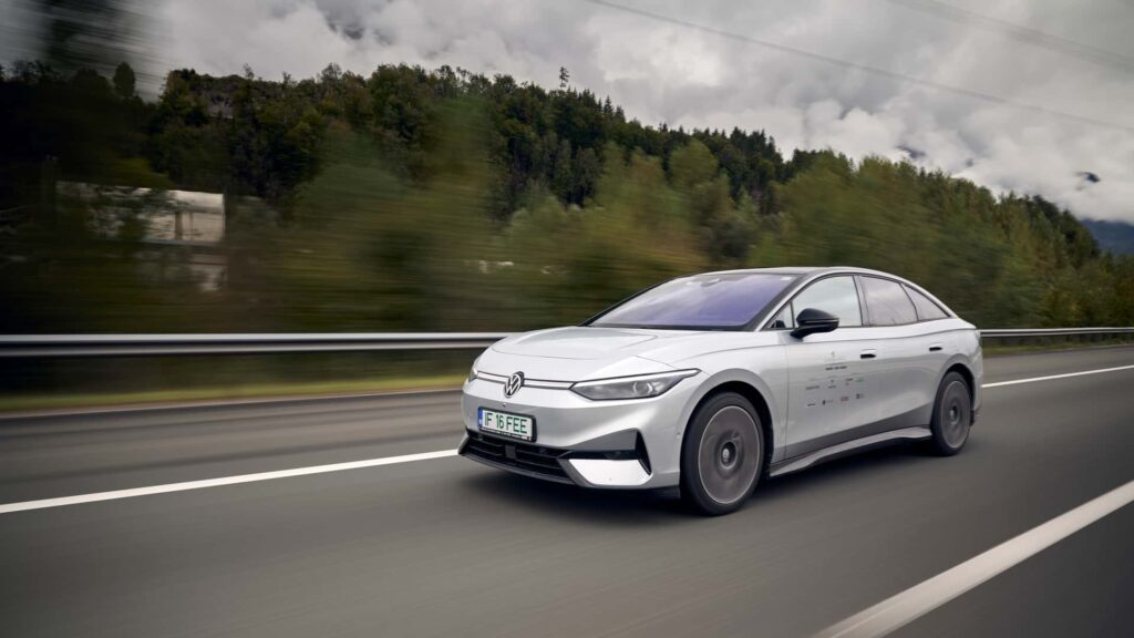 Moderne hvid elektrisk bil kører på motorvejen omgivet af natur