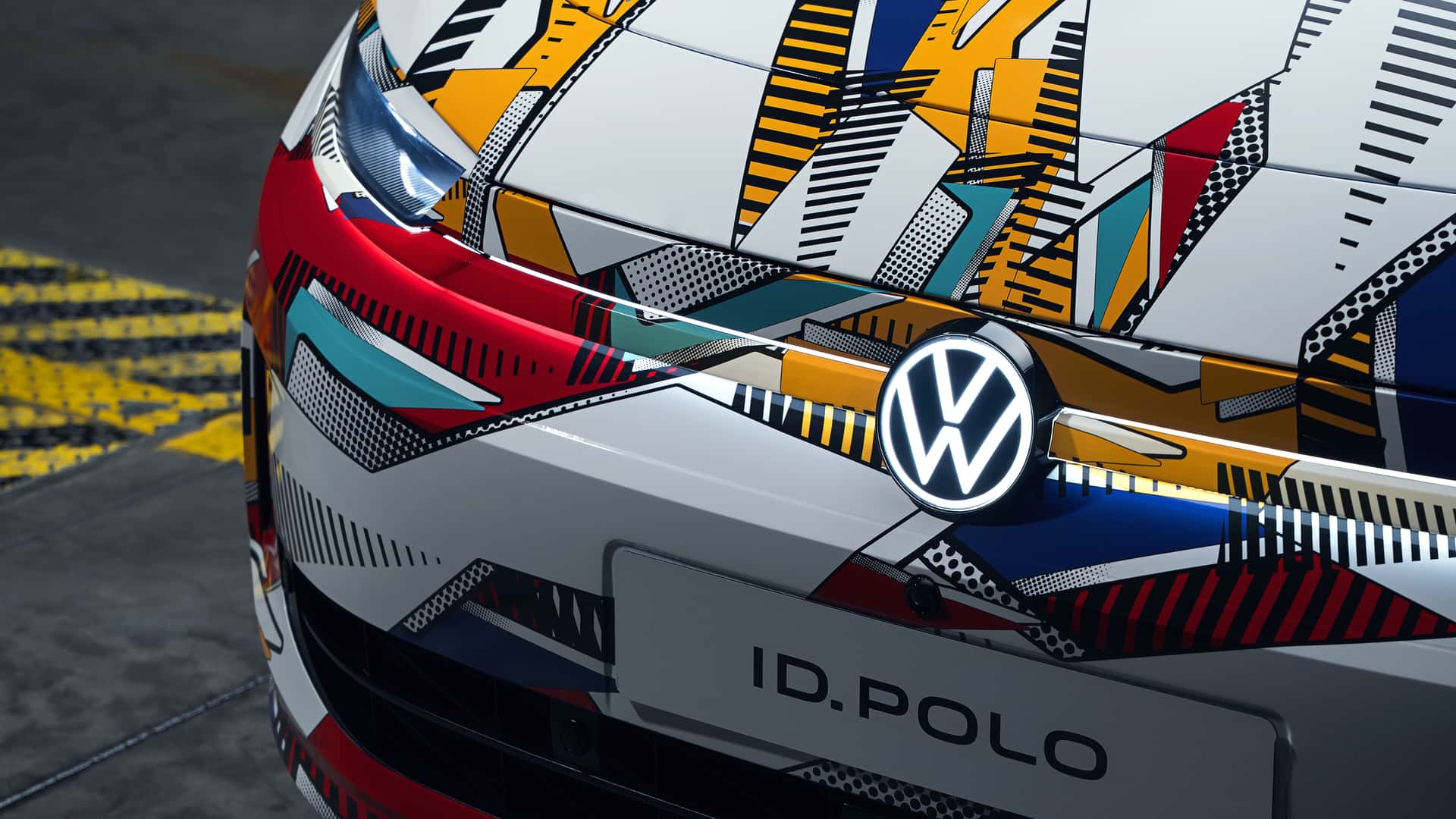 Nærbillede af en bil med farverigt, geometrisk mønster på kølergrillen og Volkswagen-logoet