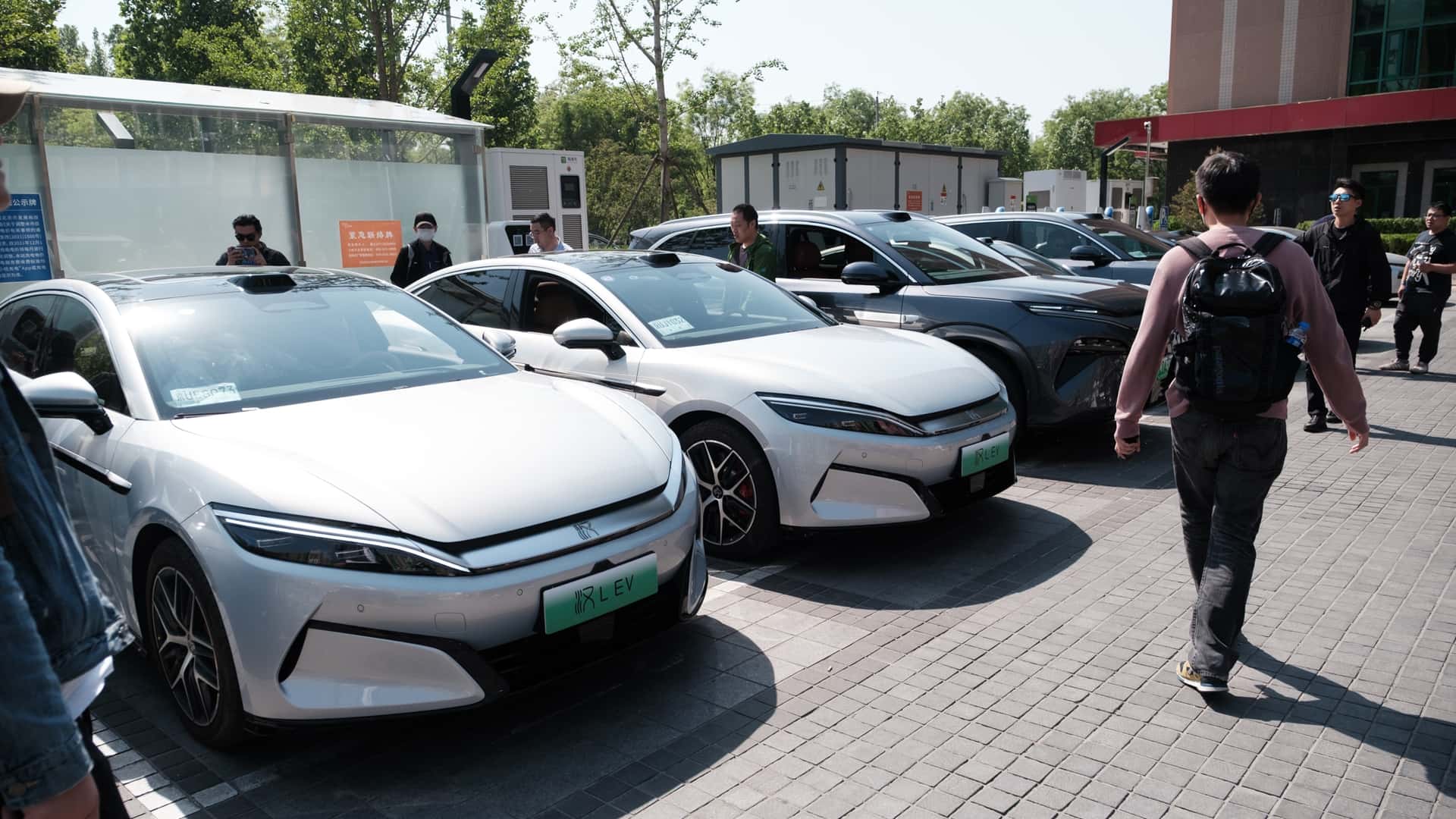 Flere elektriske biler parkeret, folk går forbi og ser på dem