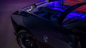 Nærbillede af en sort Tesla bils aerodynamiske design med futuristiske neonbelysning i baggrunden.
