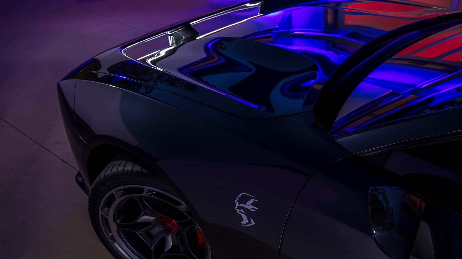 Nærbillede af en sort Tesla bils aerodynamiske design med futuristiske neonbelysning i baggrunden.