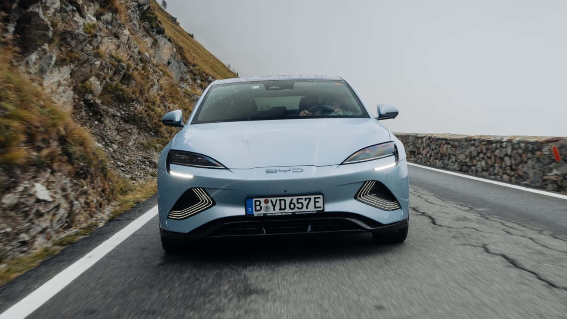 Elektrisk bil kører på bjergvej med dramatisk landskab