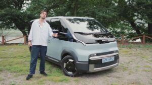Mand står ved siden af en moderne elektrisk bil parkeret udenfor