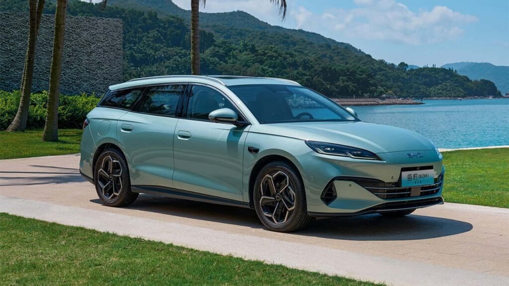 Elektrisk bil parkeret ved havet med bjerge i baggrunden på en solskinsdag