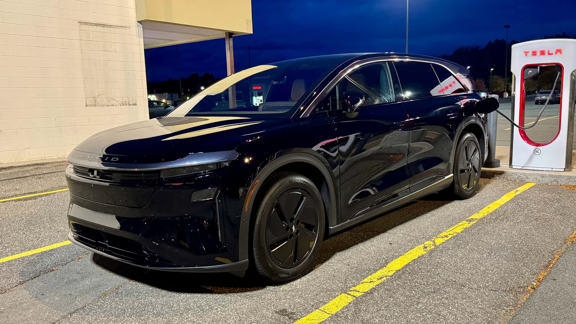 Sort elektrisk bil oplader ved Tesla ladestation om natten