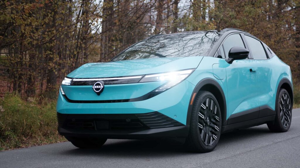 Turkis Nissan crossover elbil parkeret på en skovklædt vej