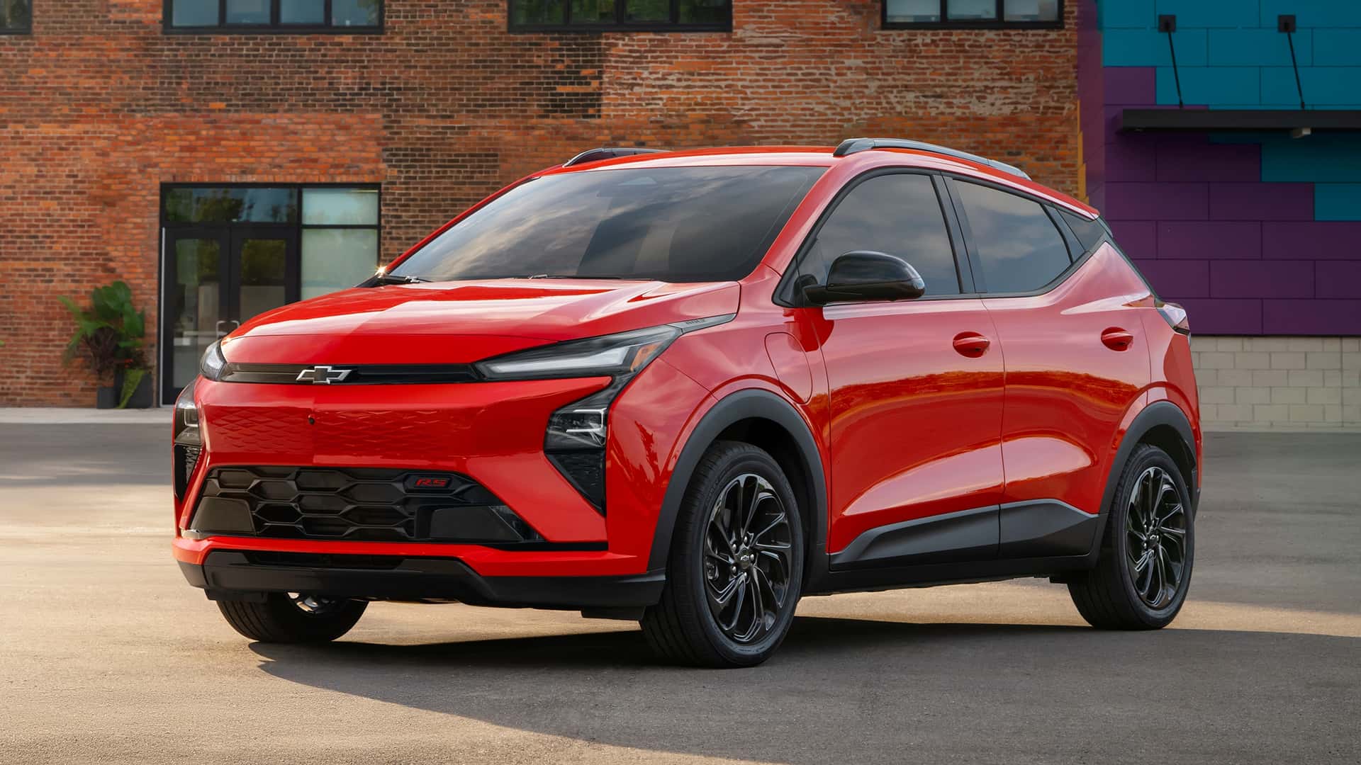 Rød elbil parkeret foran murstensbygning