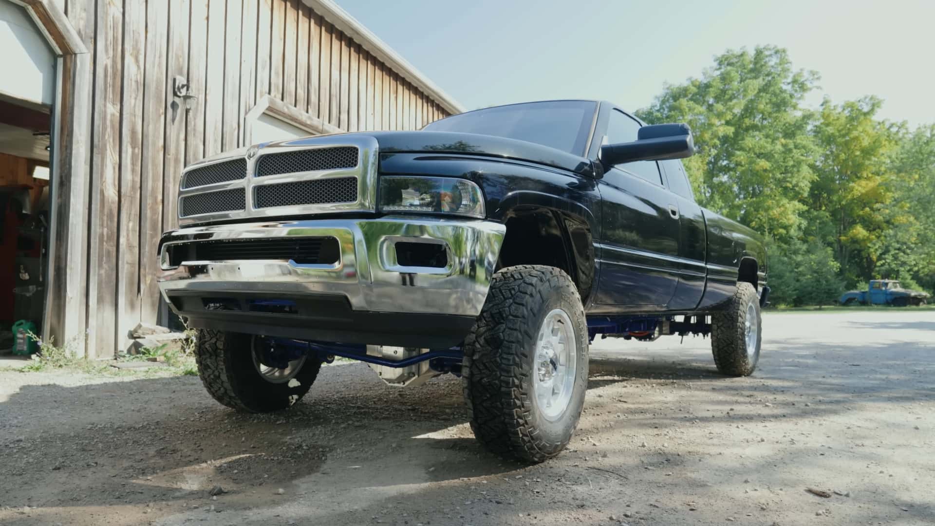 Sort pickup truck parkeret ved siden af en træbygning, set fra siden